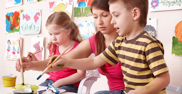 A nanny paints with children