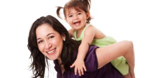 A nanny gives a small child a piggy back ride