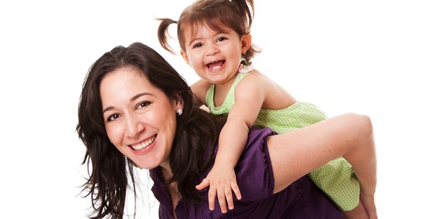 A nanny gives a small child a piggy back ride