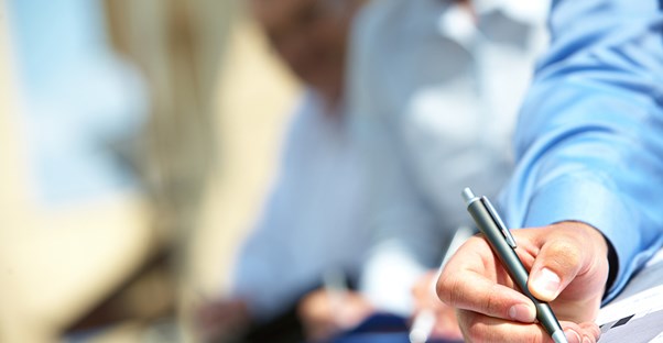 A person wearing a blue shirt holds a pen