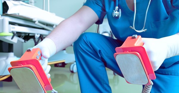 a doctor about to use a defibrillator
