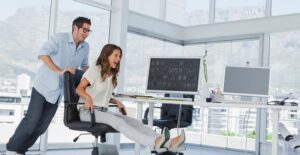 A man pushes his coworker around in an office chair