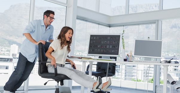 A man pushes his coworker around in an office chair
