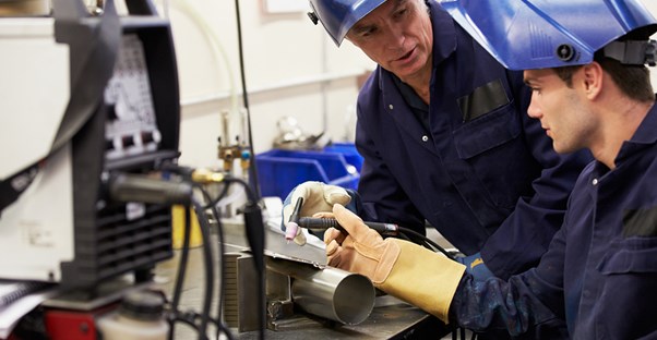 Two welders discuss a welding tool