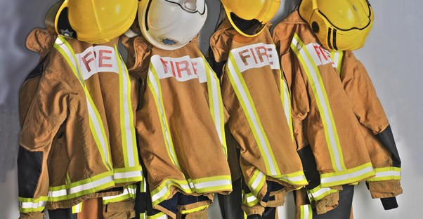 Firefighter attire hangs on a wall