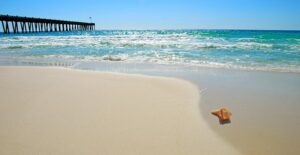 a pier extends beyond the Gulf Shores beach into the Gulf of Mexico
