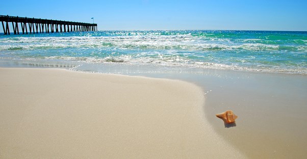 a pier extends beyond the Gulf Shores beach into the Gulf of Mexico