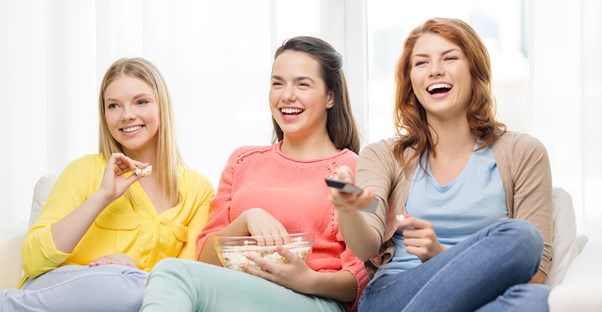 Three friends laughing as they watch Parks and Rec
