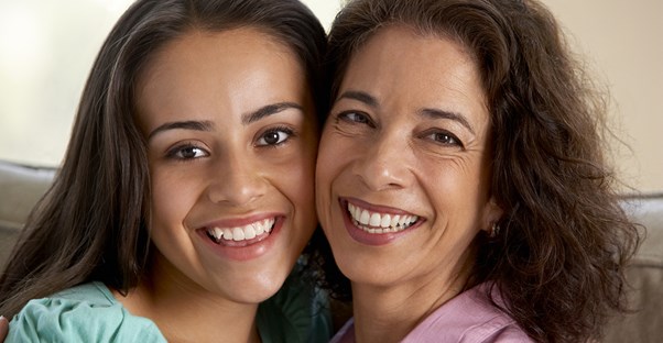 A mother hugging her teenage daughter.