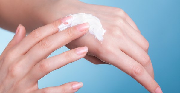 Woman moisturizing her dry winter skin.