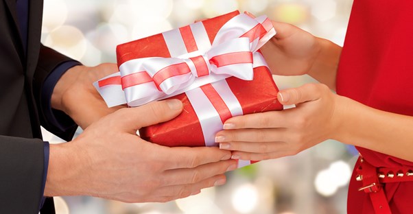 Woman giving a Valentine's Day gift to her boyfriend.