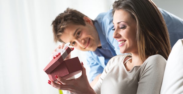 Man watching his girlfriend open her Valentine's Day gift.