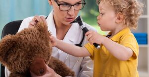 A pediatrician and a little girl play doctor with a stuffed bear