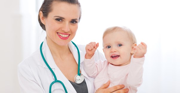 A pediatrician holds a toddler