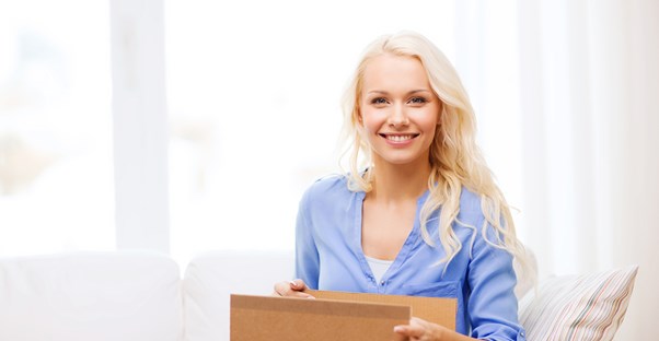 Woman smiling as she opens her subscription box order.
