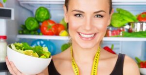 A dietitian holds up a bowl of healthy fruits and veggies