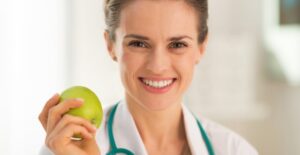 A dietitian holds an apple and smiles