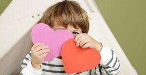 A toddler holding Valentine cards he made.