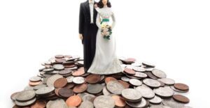 Wedding cake topper on top of a pile of coins