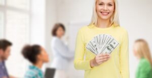 A young teen holds up the money she earned from her summer job