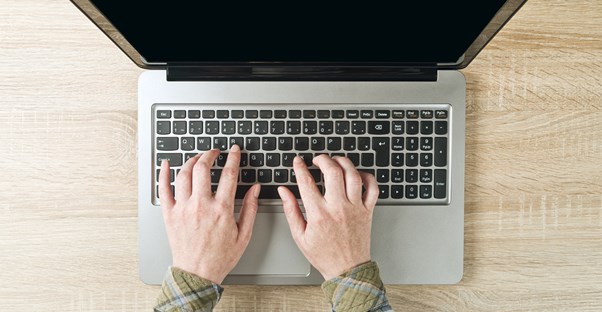 Someone types on the keyboard of a laptop