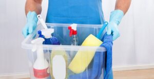 A woman holding a bucket of freshly cleaned tools.