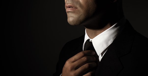 A man in a suit fixes his tie
