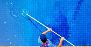 Young man cleans out a dirty pool