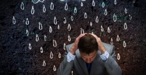 A man sits under fake rain from a fake rain cloud