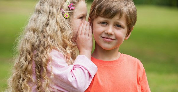 A little girl telling her brother a secret