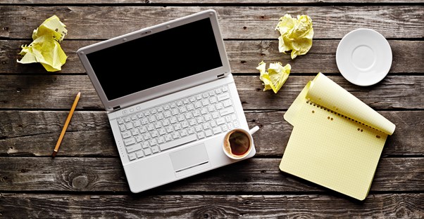 The desk of a journalist filled with coffee and crumpled paper