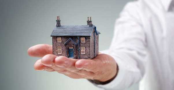 Man holding a tiny house on his hand