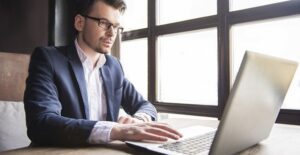 A young professional types up a work email on his laptop