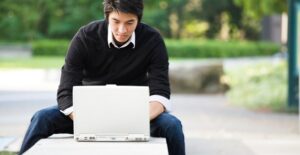 A young summer school student works on his laptop