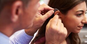 A doctor inserts a hearing aid in a young girls ear