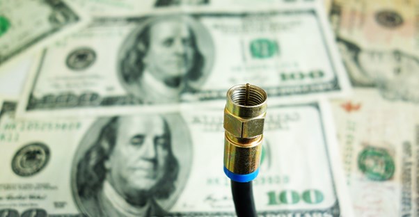 An image of a stack of money behind an unused cable cord