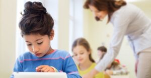 A small child using a tablet in class