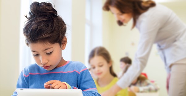 A small child using a tablet in class