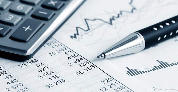 Pen laying next to a calculator on a printout of fund performance