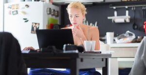 Woman works on her laptop in her kitchen