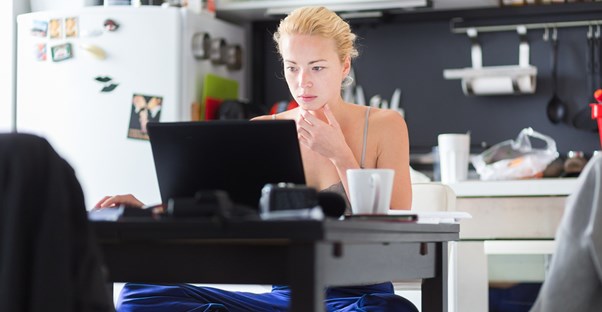 Woman works on her laptop in her kitchen