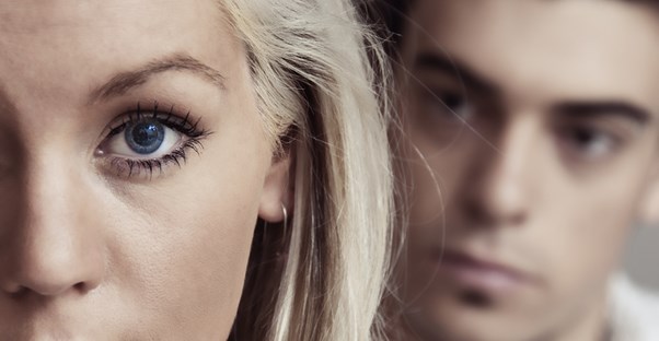 A woman with a man behind her to demonstrate domestic violence