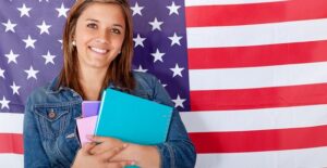 A young girl stands in front of an American flag