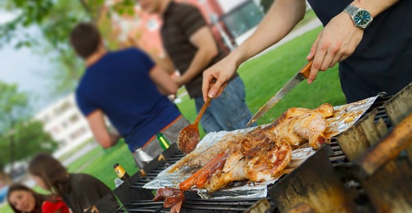 A guest helping grill at a tailgate