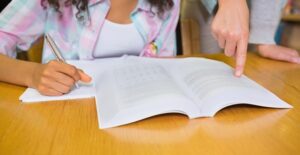 A tutor helps a young student write a paper