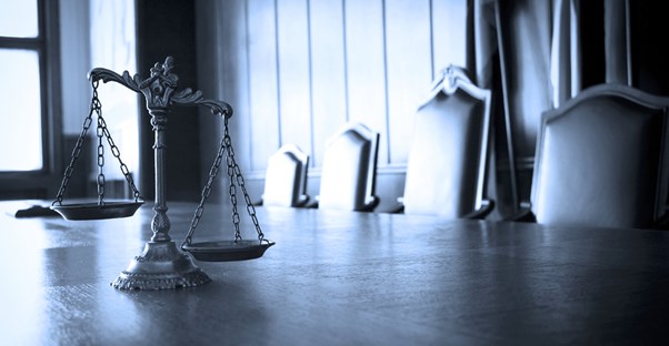 Photo of a courtroom with scales of justice in the foreground