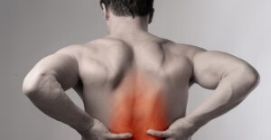 a man reaches toward pain in his lower back