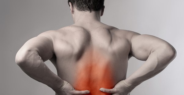 a man reaches toward pain in his lower back