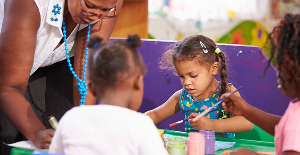 An art teacher paints with her students