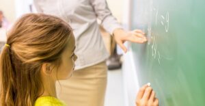 A student works out a math problem on the chalkboard